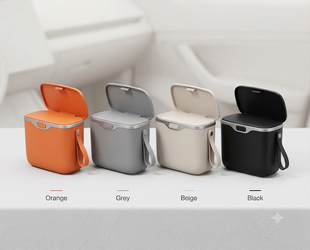 Four small square trash bins with hinged lids are shown side by side on a white surface. The bins come in orange, grey, beige, and black, with the lids open.